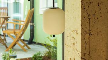 A modern interior with hanging spherical light fixtures, a wooden chair, and a table outside a window.