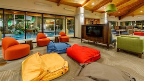 Un amplio espacio interior con vistas a la piscina, asientos cómodos y un televisor.