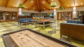 Un espace de loisirs équipé d’une table de billard, de sièges et d’une table de jeu de palet.