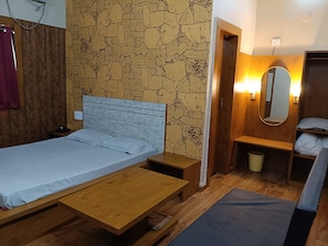 A single bed with a wooden headboard, a small bedside table, a bench, and a wall-mounted mirror.