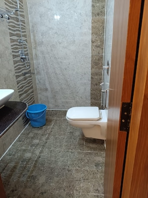 A bathroom with a toilet, a sink, and a shower area.