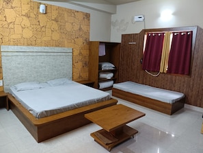 A bedroom with a large bed, a smaller bed, a wooden bench, and a wardrobe.