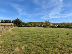 A grassy field with a fence, trees, and houses in the background. - Kate's cozy home in Burgundy. (Bray)