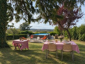 An outdoor dining area with checkered tables and chairs, a hot tub, and a view of the countryside. - Kate's cozy home in Burgundy. (Bray)
