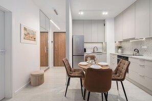 Een moderne keuken met een eethoek, met een houten deur, roestvrijstalen apparatuur en een marmeren aanrecht.