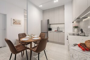 A modern kitchen with a dining area, equipped with a refrigerator, stove, and sink. - Lumina 2 rooms apart I Warsaw center (Warszawa)