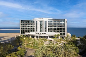 Un hotel modern amb un atrium central, envoltat de palmeres i vistes a l'oceà.