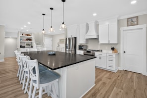 A modern kitchen with a central island, white cabinetry, and a wooden floor. - Eagles Nest | Gated Community, Beach, Golf & Ping Pong (Georgetown)