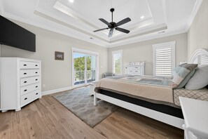 A bedroom with a bed, a dresser, a ceiling fan, and a view of the outdoors. - Eagles Nest | Gated Community, Beach, Golf & Ping Pong (Georgetown)