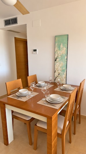 A dining area with a wooden table set for four, equipped with plates, glasses, and cutlery.