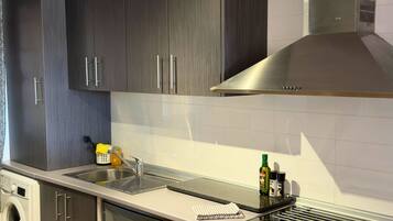 Una cucina moderna con mobili in legno scuro, una cappa aspirante in acciaio inossidabile, un forno integrato e una lavastoviglie.