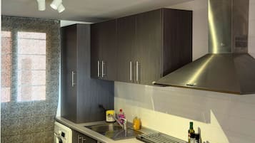 Een moderne keuken met donkere kastjes, roestvrijstalen apparatuur en een inbouwoven.