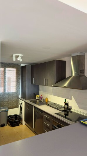 A modern kitchen with dark cabinets, stainless steel appliances, and a built-in oven. - Mar Menor Golf Resort 2-Bedroom Apartment | Golf & Lake Views (MC)