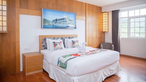A hotel room with a bed, a nightstand, a chair, a painting of a cruise ship, and a window with curtains. - Tranz MAV Hotel Samarinda (Samarinda)