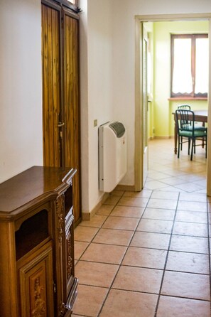 A hallway with a wooden cabinet, a white radiator, and a dining area with chairs and a table. - Ca` D'la Pèisa - Odalengo Grande (Sant`Antonio)