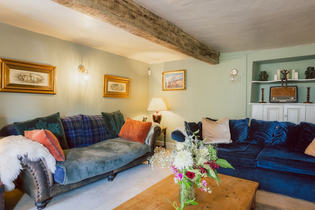 A living room with two sofas, a coffee table with flowers, wall-mounted lamps, and framed pictures.