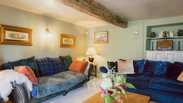 A living room with two sofas, a coffee table with flowers, wall-mounted lamps, and framed pictures.