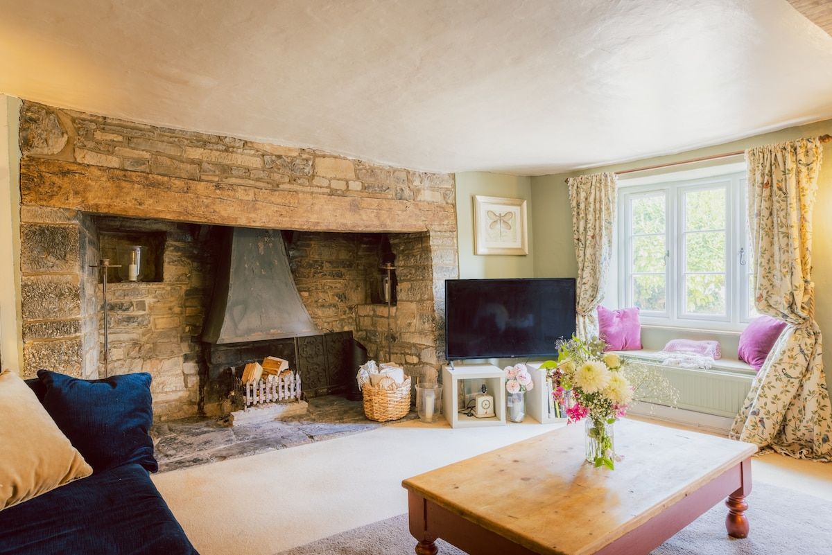 A cozy living room with a stone fireplace, a flat-screen TV, and a comfortable sofa.