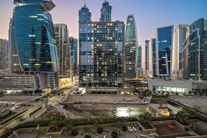 A modern cityscape with high-rise buildings, a construction site, and a landscaped area with seating. - Near Metro  1BR  Pool view & Prime Location (Dubai)