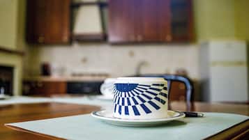 Una taza con un diseño azul y blanco sobre un platito, colocada sobre una mesa con un posavasos.