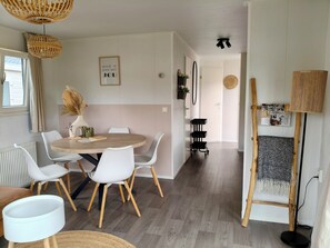 Een moderne eetruimte met een ronde tafel, witte stoelen en een hanglamp.