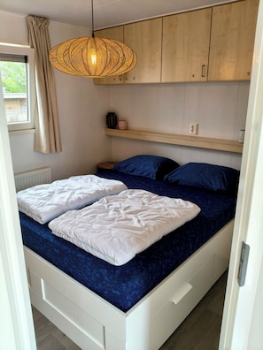 Ein Schlafzimmer mit einem Bett, einer Hängeleuchte und Holzschränken.