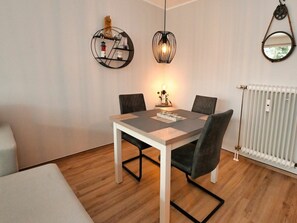 Ein Essbereich mit Tisch und Stühlen, einer Pendelleuchte und einem an der Wand befestigten Spiegel.