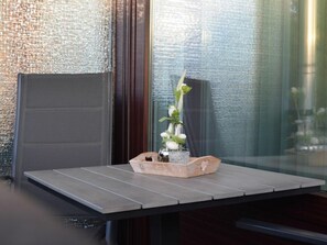 Ein modernes Interieur mit einem Holztisch, einer Vase mit weißen Blumen und einer strukturierten Wand.