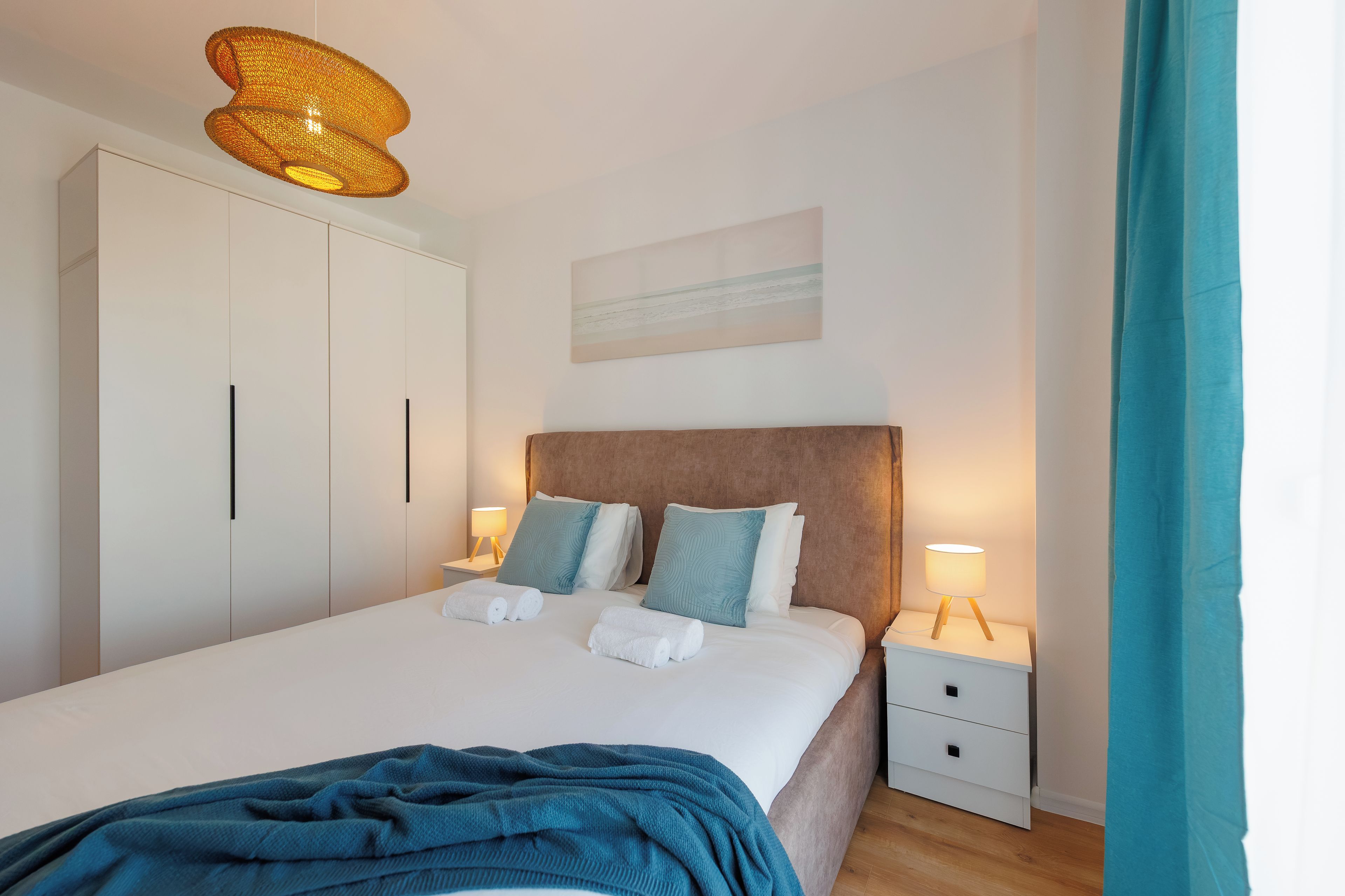 Une chambre d’hôtel avec un lit, des tables de chevet, une armoire et un tableau au mur.