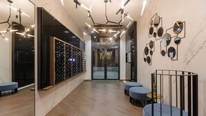 Un hall d’entrée moderne avec un plancher en bois, un coin salon avec des chaises bleues, un meuble à vin et un mur orné de miroirs ronds.