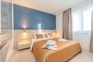 A modern hotel room with a large bed, bedside tables, a reading area, and a view of the outdoors. - Villa Nexia With Private Pool (Sibenik)