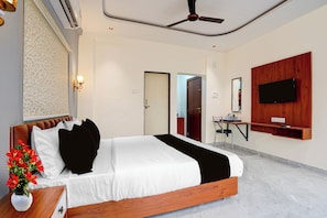 Habitació d'hotel moderna amb un llit gran, un ventilador de sostre, un televisor penjat i una petita zona d'escriptori.