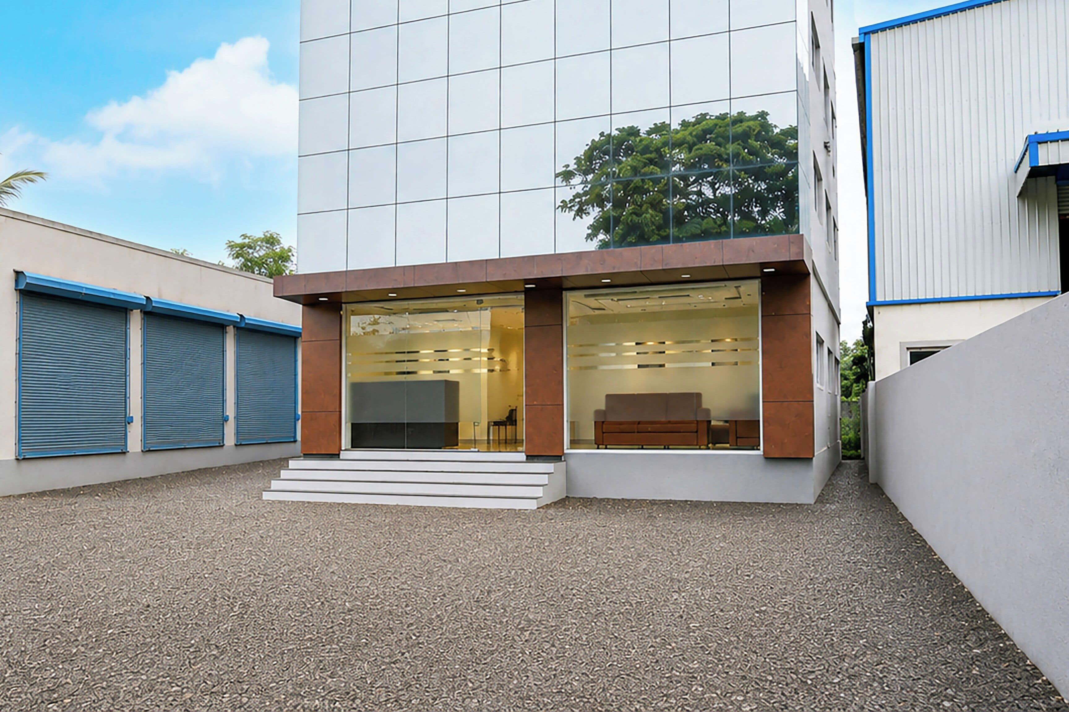 A modern building with a glass facade, a set of steps leading to the entrance, and a clear sky.