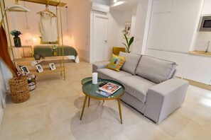 A modern living room with a sofa, a glass coffee table, a hanging chair, and a small side table with a magazine. - Housing Ollerias by Sharingco (Málaga)