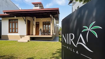 Eine moderne Villa mit überdachter Veranda, einer Treppe zum Eingang und dem Logo von NIRA Villa.