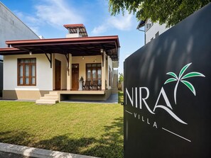A modern villa with a covered porch, a staircase leading to the entrance, and a logo for NIRA Villa.