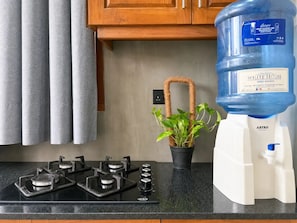 A kitchen with a gas stove, a water dispenser, and a potted plant.