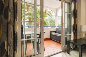 A balcony with a table and chairs, a sofa, and a lamp. - El Limonar by Sharingco (Málaga)
