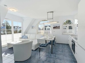 A modern interior with a dining area, kitchen, and seating space. - Evening - Apartment 4 (Zingst)