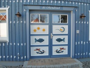 A blue building with a door featuring nautical-themed decorations. - Evening - Apartment 4 (Zingst)