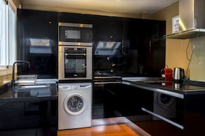 Une cuisine compacte équipée d’un lave-linge, d’un four à micro-ondes et d’un four encastré.