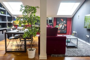 A modern living room with a dining area, featuring a large plant, a red sofa, and a glass coffee table. - Mlgsa023san4a - San Lorenzo (Málaga)