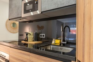 Eine moderne Küche mit Spüle aus Edelstahl, Backofen und Mikrowelle.