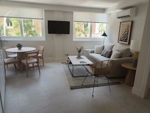 Ein modernes Wohnzimmer mit Sofa, Couchtisch und Essbereich.