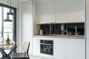 A modern kitchen with a glass dining table, wicker chairs, and a built-in oven. - Mlgsa002don3b - Don Rodrigo (Málaga)