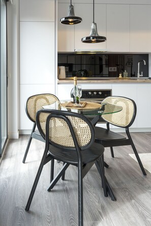 A modern kitchen with a dining area featuring a glass table and woven chairs. - Mlgsa002don3b - Don Rodrigo (Málaga)