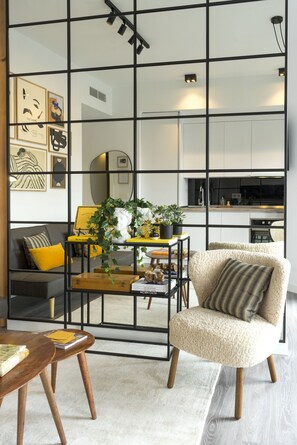 A modern living room with a sofa, armchair, and coffee table, featuring artwork and a potted plant. - Mlgsa002don3b - Don Rodrigo (Málaga)