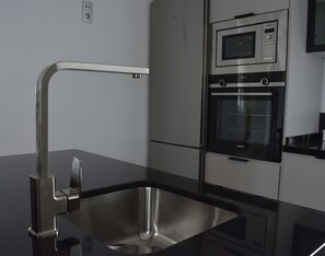 A modern kitchen with a stainless steel sink, a built-in oven, and a microwave. - Mlgsa032gra7izq - Calle Granada (Málaga)