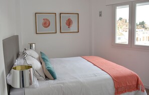Une chambre à coucher avec un lit, des oreillers, une lampe de chevet et deux tableaux encadrés accrochés au mur.