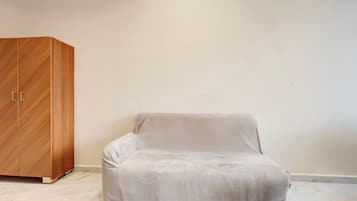 A room with a white sofa and a wooden wardrobe.